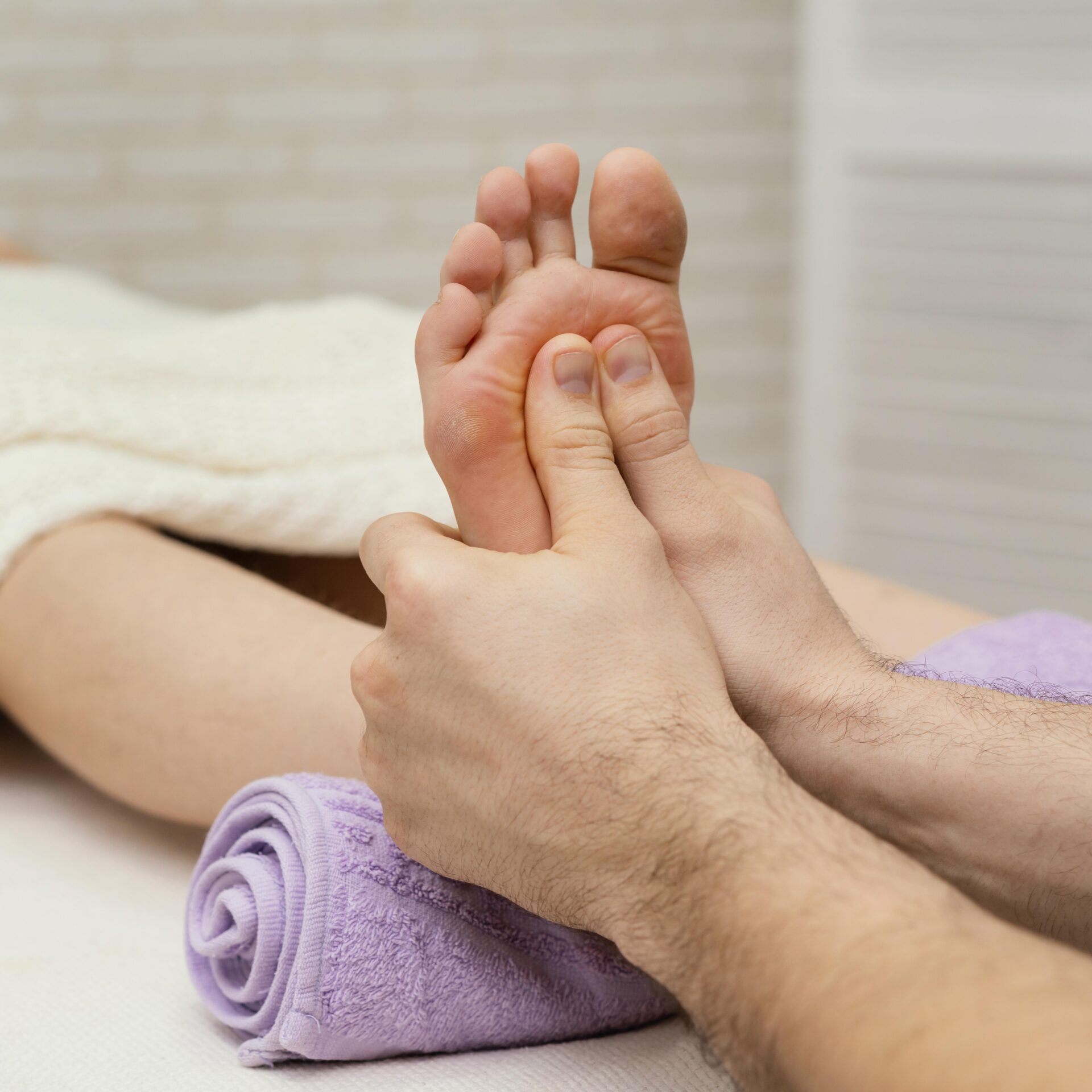 Therapist's hands gently massaging a foot's sole, close-up view